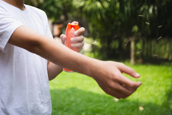 stock image Young boy spraying insect repellents on skin in the garden with mosquito flying