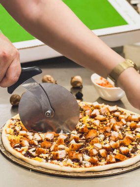 Chef hands cutting pizza on table in restaurant clipart