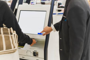 Havaalanı personeli, havaalanındaki uçuş kartlarını kontrol eden bir kadına yardım ediyor..