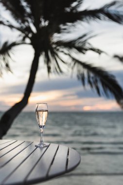 Gün batımı kumsalında masada bir kadeh Champange.