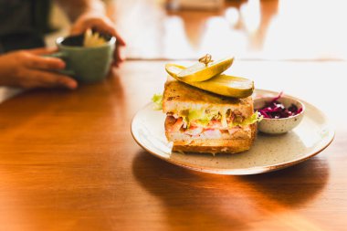 Cheese sandwich with pickle on a plate in cafe clipart