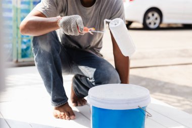 Tencerede beyaz renkli boya ile boya silindiri.