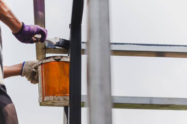 Ev dekorasyonunda çeliğe paslanma önleyici boya çizen adam.