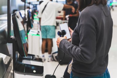 Kadın kendini havaalanında el taraması barkoduyla kontrol ediyor.