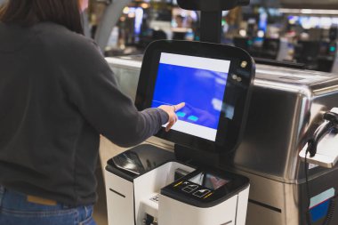 Havaalanına giriş yapmak için servis makinesini kullanan kadın.