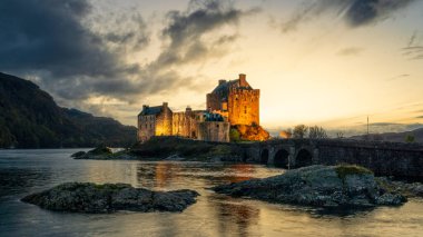 Eilean Donan (İskoçya) şatosu bulutlu bir akşamda altın saatinde aydınlandı