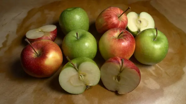 Ahşap bir masada ısırılmış yeşil elma ve gala elmaları grubu.
