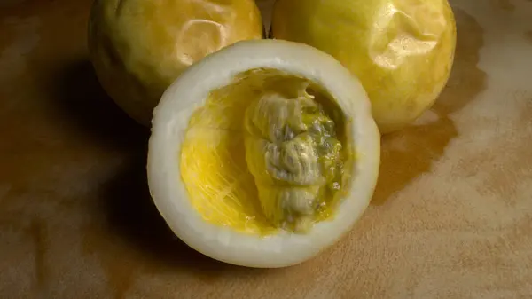 Tahta bir masada dilimlenmiş çarkıfelek meyvesi olan bir grup tutku meyvesi yakın plan.