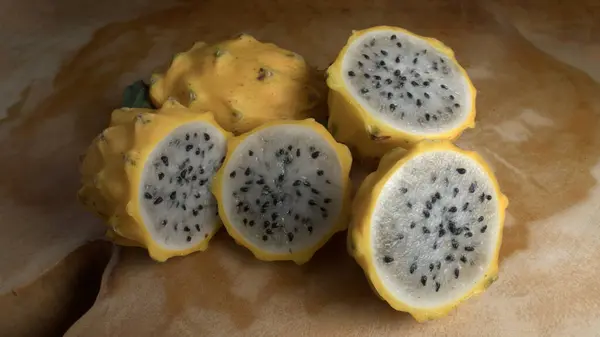 Tahta bir masada dilimlenmiş ejderha meyveleri grubu.