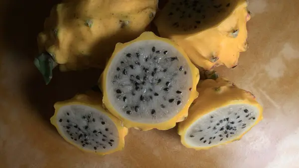 Tahta bir masanın üstünde dilimlenmiş ejderha meyveleri grubu.