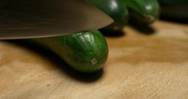 Avrupa salatalığı ahşap bir masada kesiliyor, yakın plan.