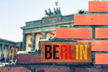 Harap olmuş tuğla duvara Berlin yazıtları ve arka planda Brandenburg kapısının bulanıklığı