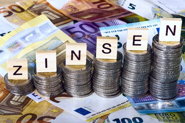 stock image close-up shot of stacks of euro coins with interest charges inscription in german on wooden cubes