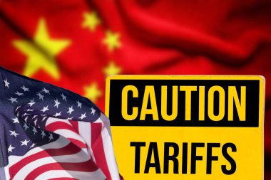 ABD ve Çin bayrakları ve Amerika 'da gümrük vergilerini gösteren bir tabela.