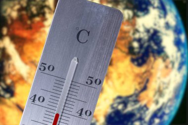 Dünya gezegeni ve yazın iklim değişikliği ve küresel ısınmanın sembolü olarak bir termometre.