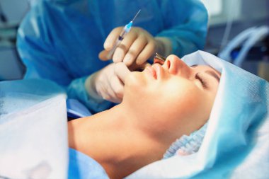 Ameliyat odasında arka planda erkek cerrah var..