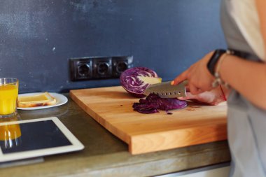 Mutfakta yemek yapmak için tablet bilgisayar kullanan genç bir kadın..