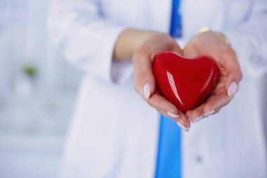 Steteskop tutan, kalbi hafif arka planda olan kadın bir doktor..