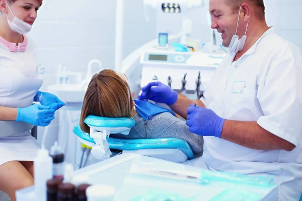 牙科诊所的资深男牙医与女病人交谈并准备治疗 — 图库照片