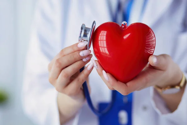 stock image A doctor with stethoscope examining red heart, isolated on white background.