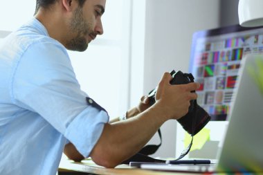 İnternette çalışırken bilgisayarın ve dizüstü bilgisayarın önünde grafik stüdyosunda oturan genç tasarımcının portresi