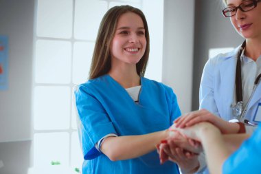 Doktorlar ve hemşireler tıbbi bir ekipte el ele tutuşuyorlar..