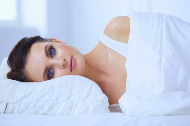 Genç ve güzel bir kadın yatakta yatıyor.