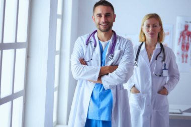 Yakışıklı doktor genç bayan doktorla konuşuyor ve ofisinde otururken notlar alıyor.