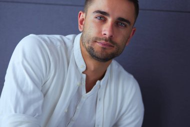 Gri arka planda yalnız oturan genç iş adamı