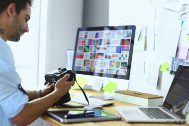 İnternette çalışırken bilgisayarın ve dizüstü bilgisayarın önünde grafik stüdyosunda oturan genç tasarımcının portresi