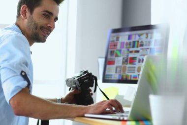 İnternette çalışırken bilgisayarın ve dizüstü bilgisayarın önünde grafik stüdyosunda oturan genç tasarımcının portresi