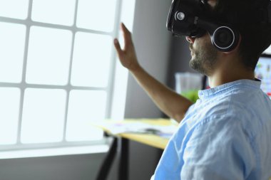 Genç erkek yazılım programcısı ofiste üç boyutlu sanal gerçeklik gözlükleriyle yeni bir uygulama test ediyor.