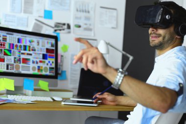 Genç erkek yazılım programcısı ofiste üç boyutlu sanal gerçeklik gözlükleriyle yeni bir uygulama test ediyor.