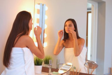 Çekici genç bir kadın yüzüne krem sürüyor..