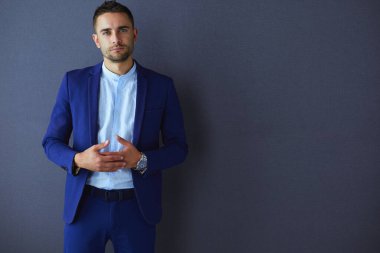 Gri arka planda yalnız oturan genç iş adamı