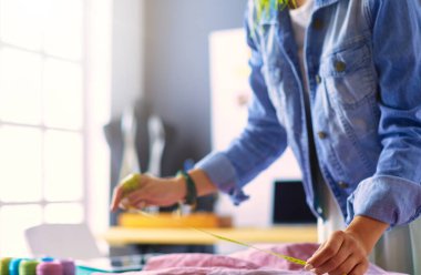 Moda tasarımcısı kadın stüdyoda tasarımları üzerinde çalışıyor.