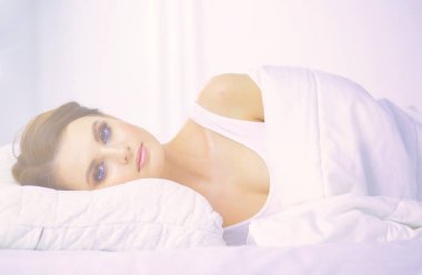Genç ve güzel bir kadın yatakta yatıyor.