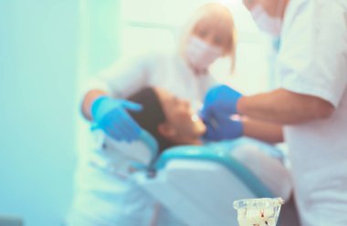 Genç bir kadının dişlerini tedavi eden bir dişçinin portresi..