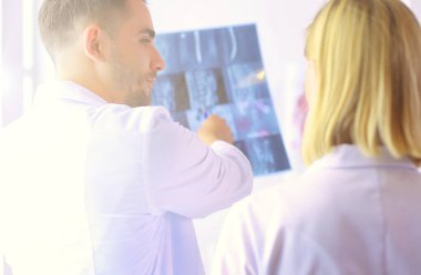 Yakışıklı doktor genç bayan doktorla konuşuyor ve ofisinde otururken notlar alıyor.