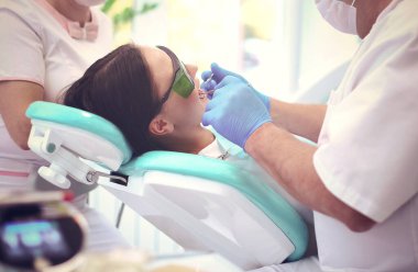 Erkek dişçi hastalarının dişleriyle uğraşıyor..