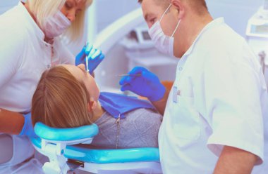 Diş hekimi ve asistanı kapsamlı bir muayene yapıyorlar..