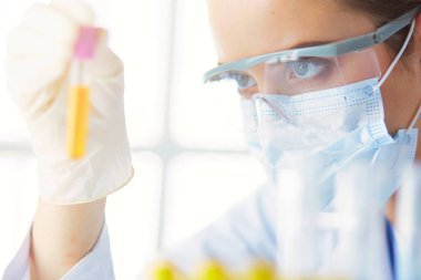 Modern laboratuvar veya hastanede plastik tıbbi tüplerle çalışan araştırmacı, doktor, bilim adamı veya laboratuvar asistanı.