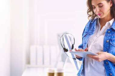 Gülümseyen kadın kahve içiyor ve kafede tablet kullanıyor.