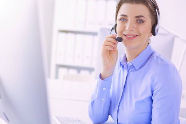 Ofisinde kulaklık takmış, telefon operatörü olarak çalışan ciddi ve güzel bir genç kadın..