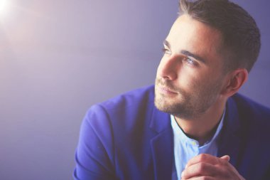 Gri arka planda yalnız oturan genç iş adamı