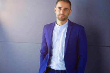 Gri arka planda yalnız oturan genç iş adamı