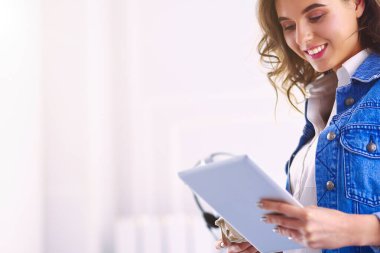 Gülümseyen kadın kahve içiyor ve kafede tablet kullanıyor.