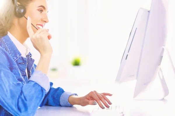 快乐迷人的年轻女性坐着 在办公室用耳机与笔记本电脑一起工作 — 图库照片