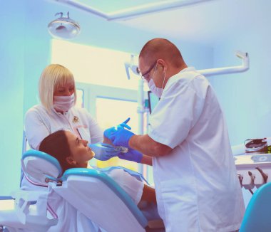 Genç dişçi ve asistanı kadını tedavi ediyor..