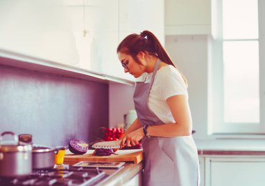 Yeni mutfakta yemek pişiren kadın sebzelerle sağlıklı yemekler yapıyor..